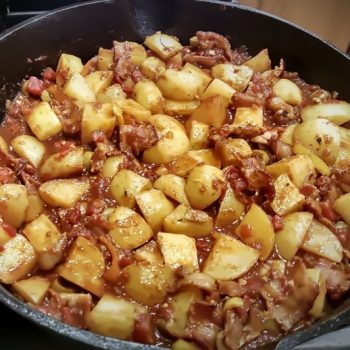 Spanish potatoes with bacon and capers in cast iron skillet