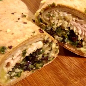 Spinach tuna sandwich wrap cut in half on wood cutting board
