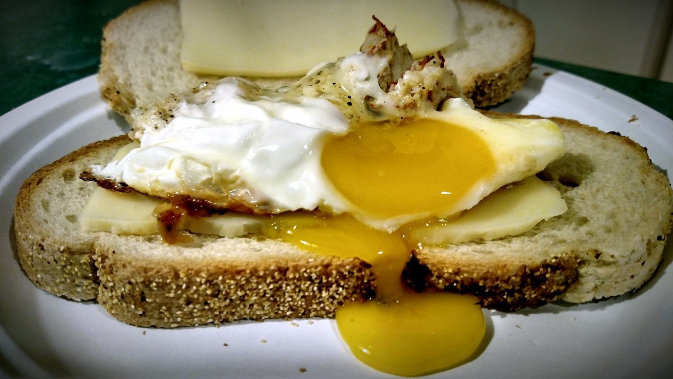 Breakfast fried egg sandwich on rye toast and Swiss cheese on a plate