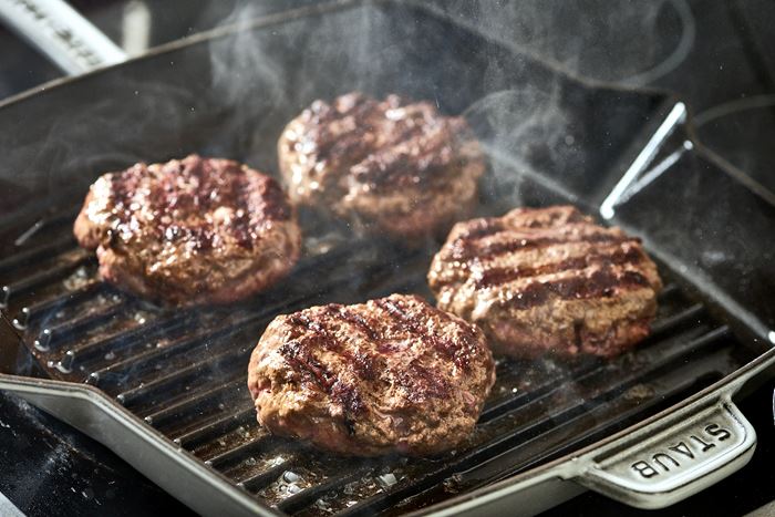 beyond meat vs real meat burgers on the grill photo